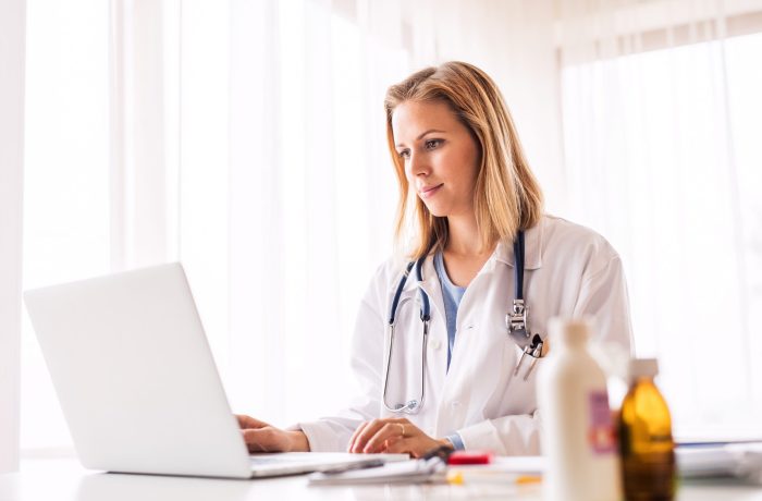 Young female doctor working on laptop at the office desk.